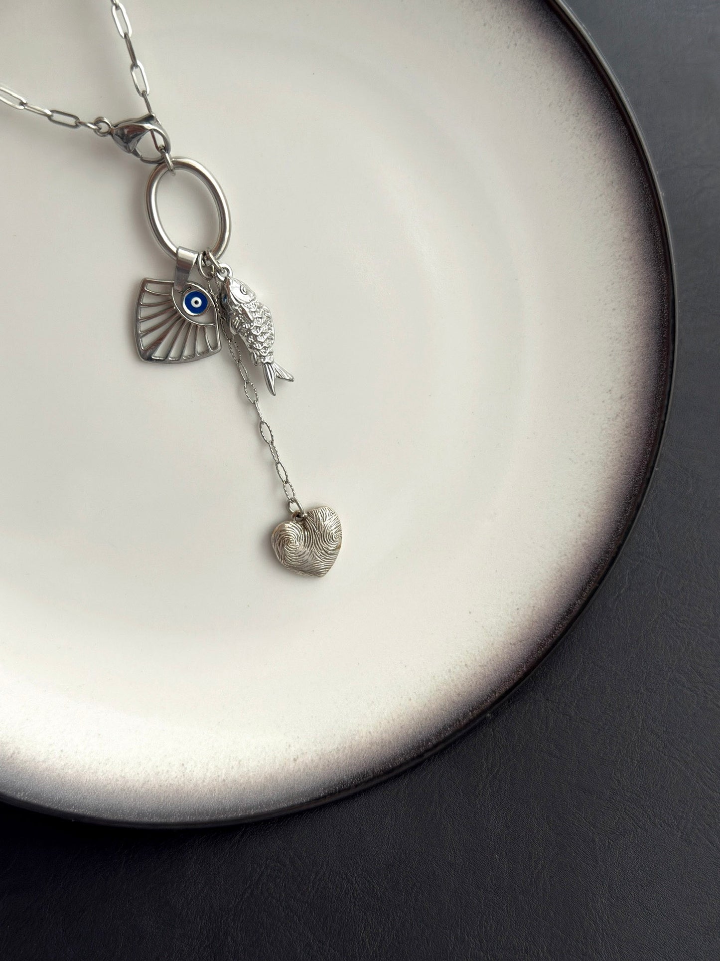 Γυναικείο κολιέ από ατσάλι σε ασημί με charms μάτι ψάρι και καρδιά σε minimal statement σύνθεση