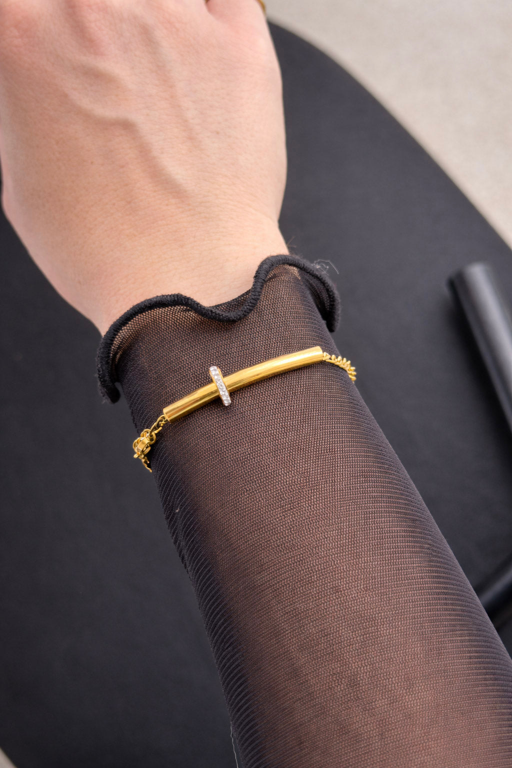 Γυναικείο βραχιόλι από ατσάλι χρυσό με αλυσίδα και κυλινδρικό στοιχείο φορεμένο