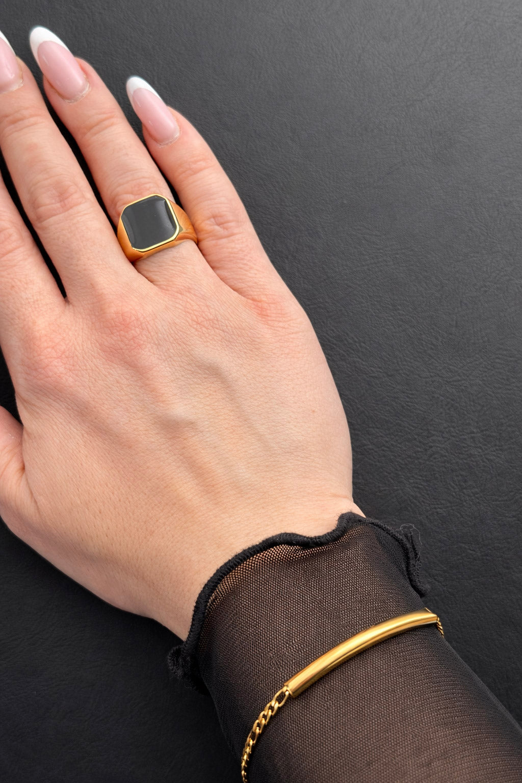 Γυναικείο signet δαχτυλίδι από ατσάλι σε χρυσό με τετράγωνο μαύρο σμάλτο φορεμένο σε χέρι