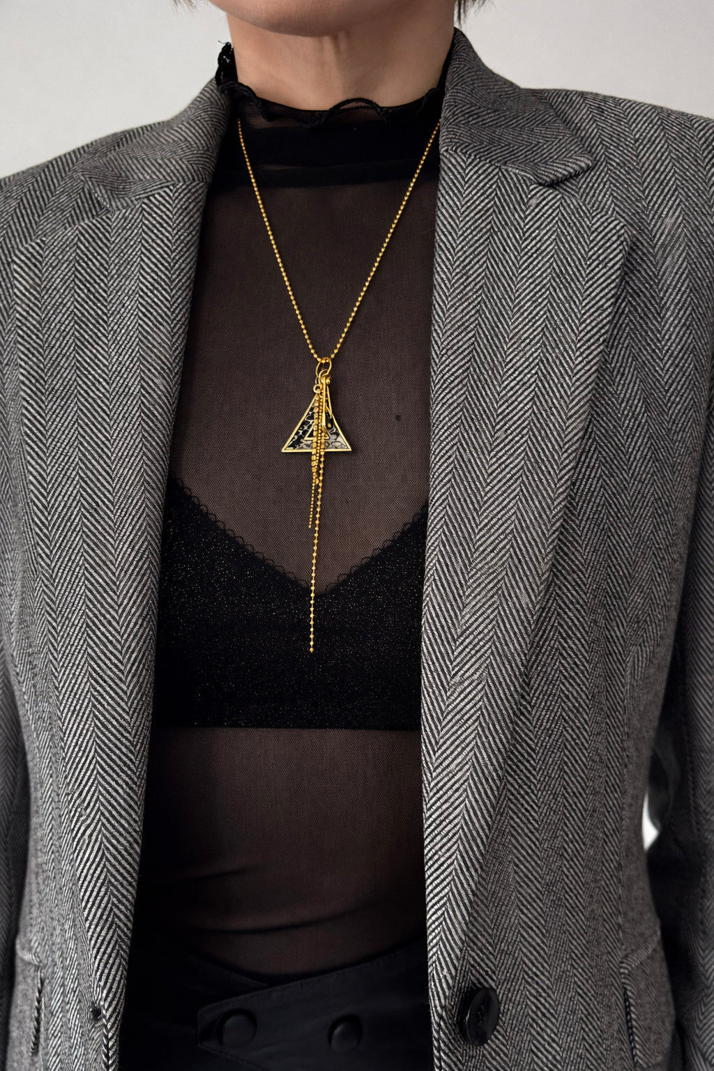 Γυναικείο κολιέ από ατσάλι σε χρυσό με γεωμετρικό τρίγωνο και αλυσίδες  φορεμένο