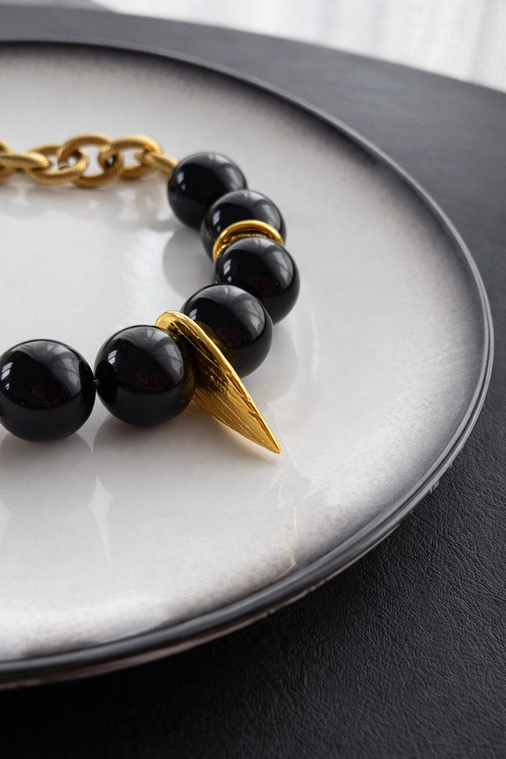Γυναικείο κολιέ από ατσάλι σε χρυσό με μαύρες πέτρες close up