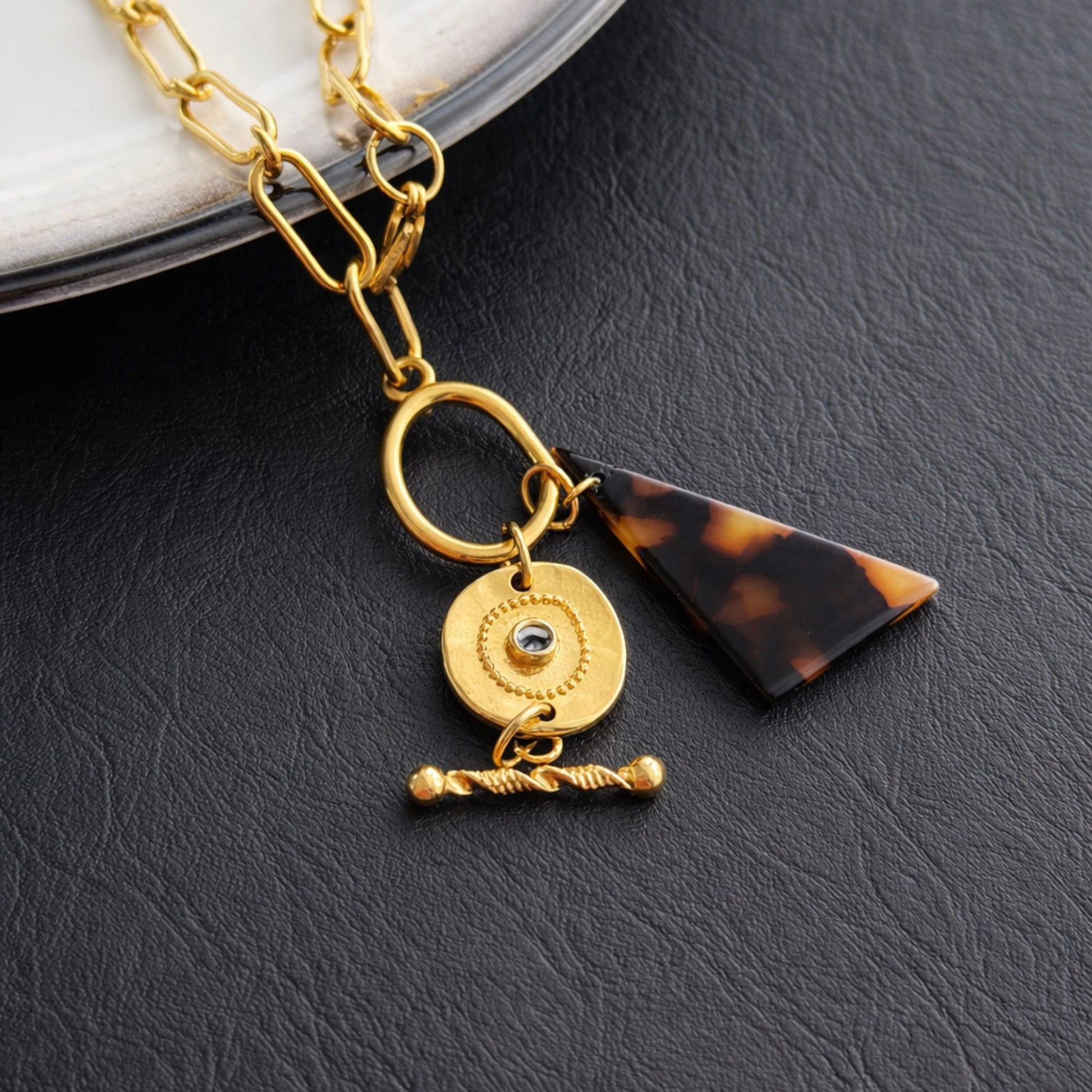 Γυναικείο χρυσό κολιέ από ατσάλι με geometric charms και ταρταρούγα λεπτομέρεια σε μαύρο φόντο