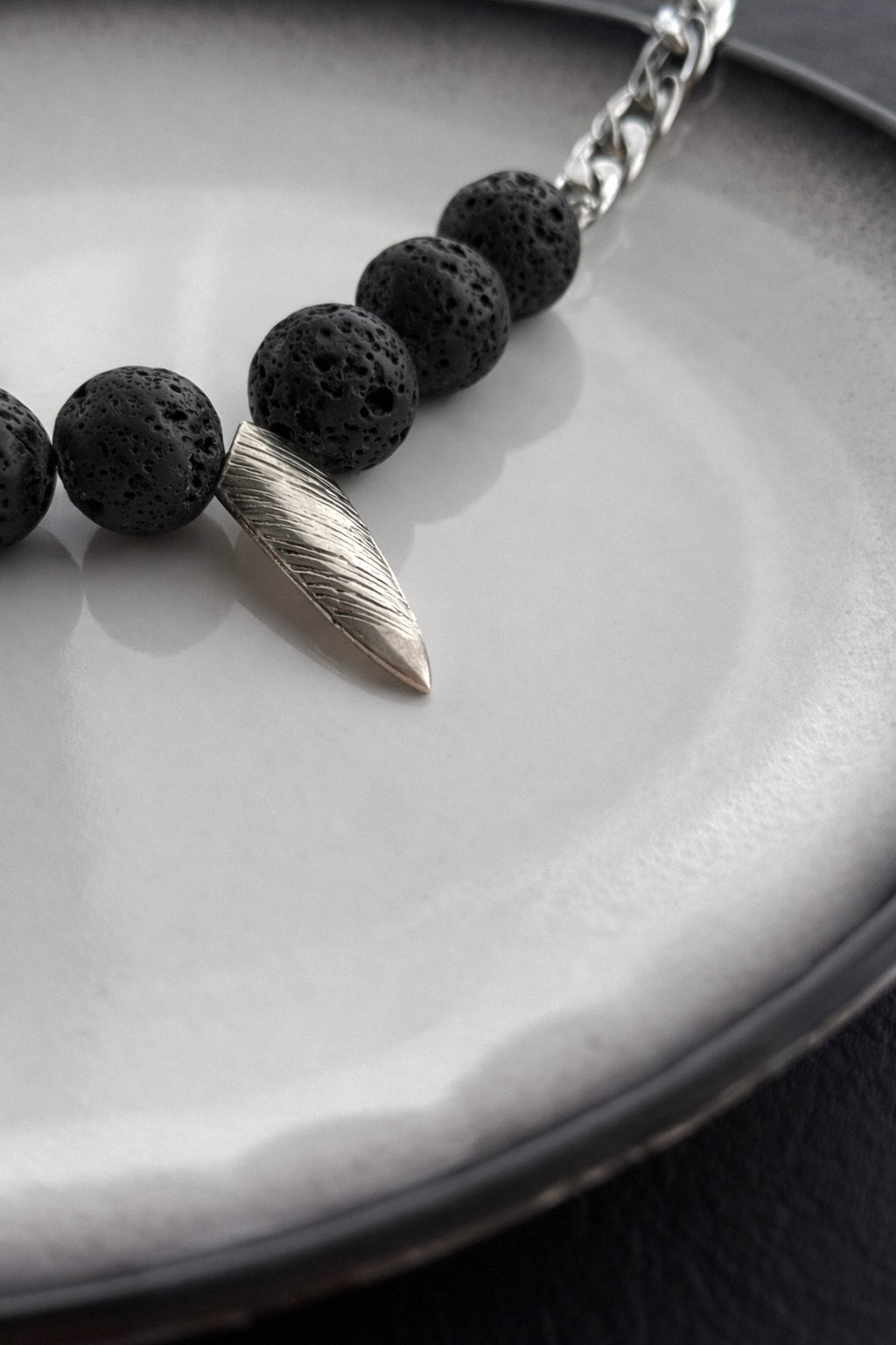 Γυναικείο κολιέ με πέτρες λάβας, ατσάλινο στοιχείο και αλυσίδα σε ασημί close up 
