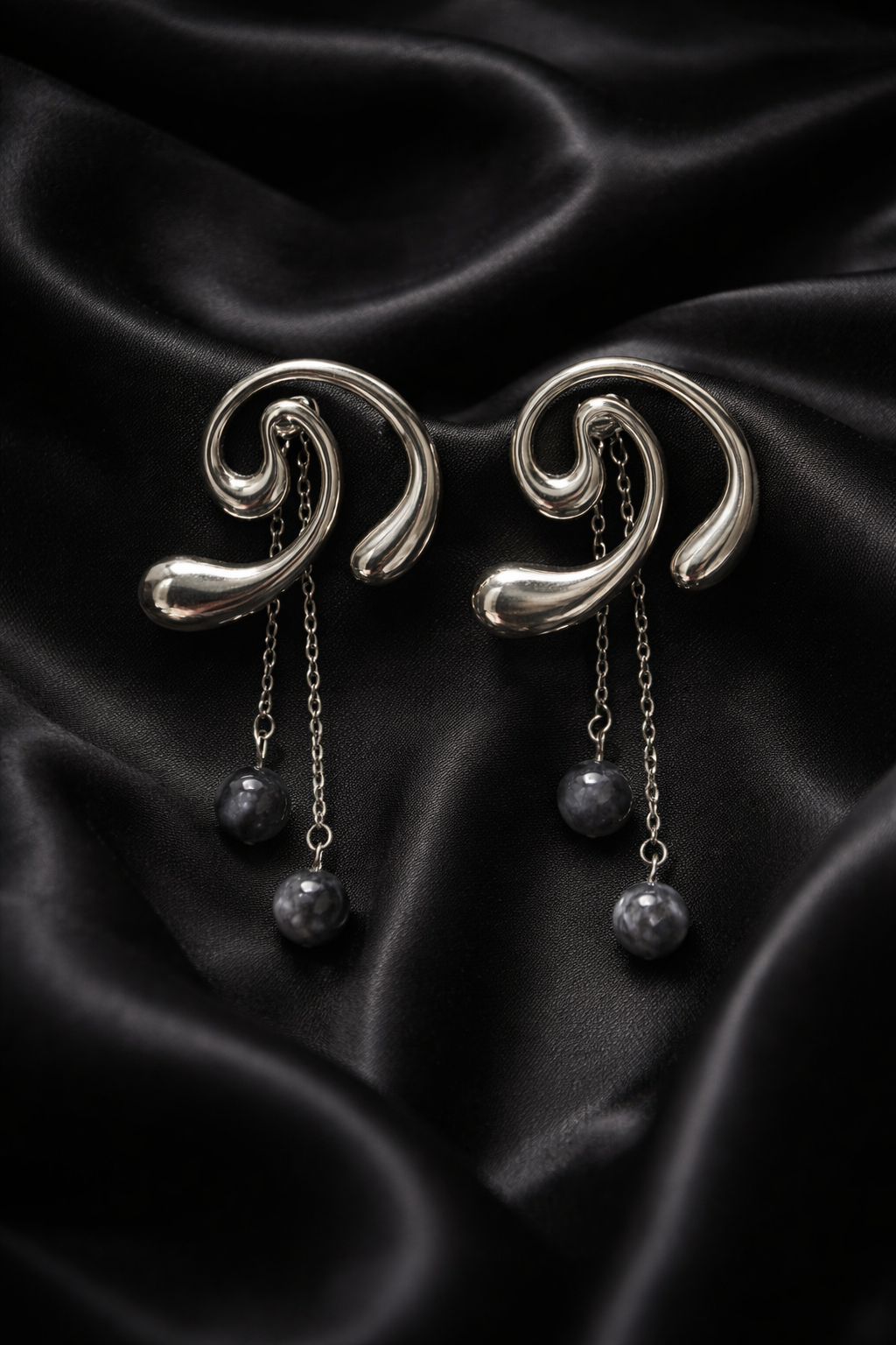 Σκουλαρίκια από ατσάλι ασημί με καμπύλες και κρεμαστά στοιχεία σε μαύρο φόντο