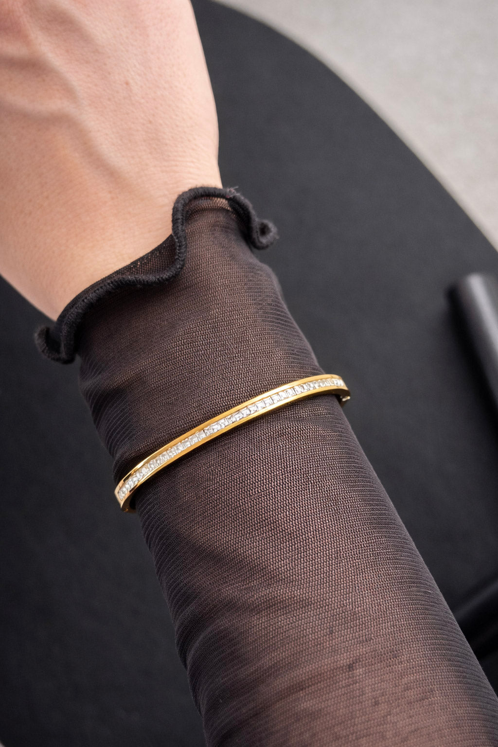 Γυναικείο λεπτό χρυσό βραχιόλι bangle από ατσάλι με διαφανή ζιργκόν σε ευθεία γραμμή φορεμένο