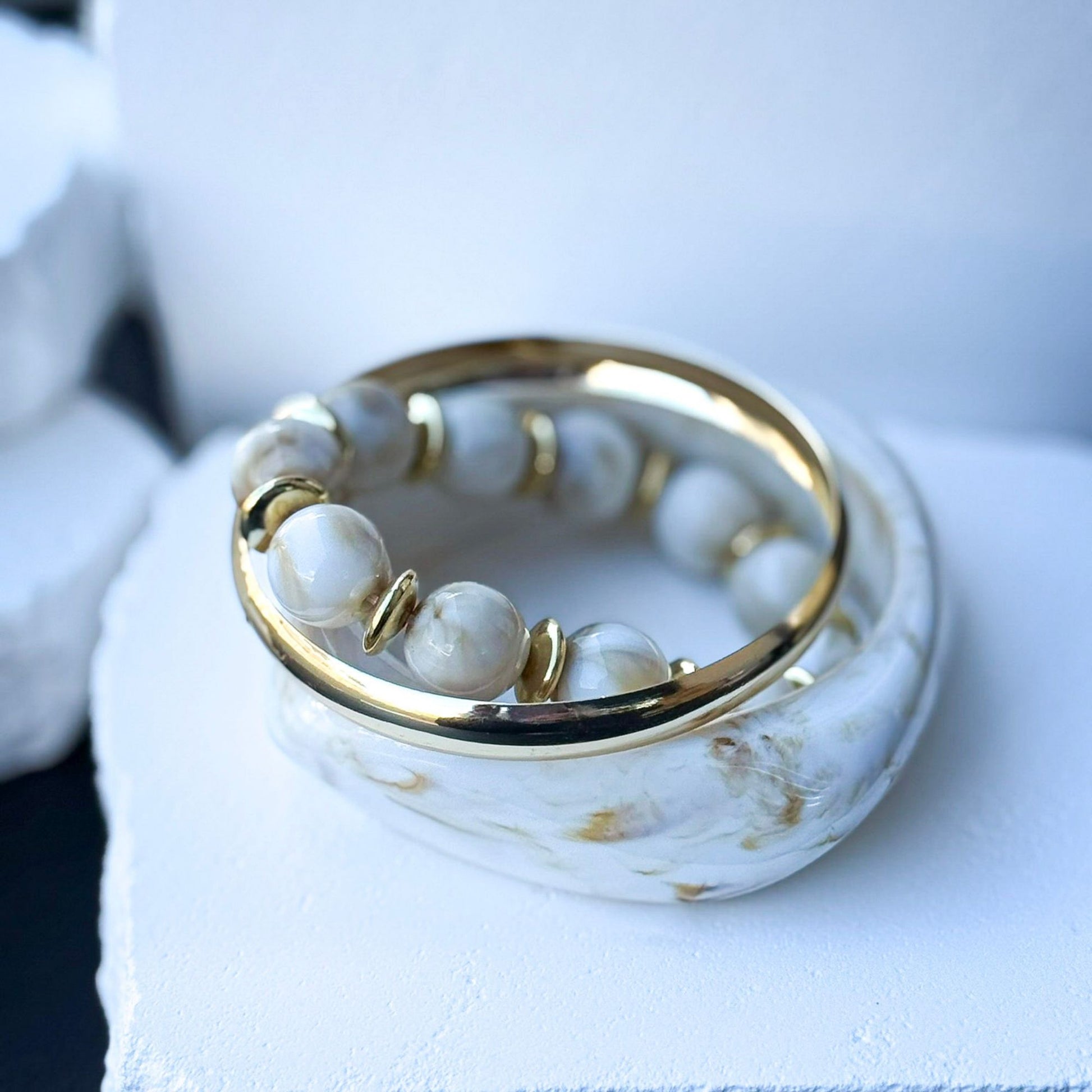 Minimal stacked βραχιόλια με creamy neutral marble χρώματα και glossy υφή