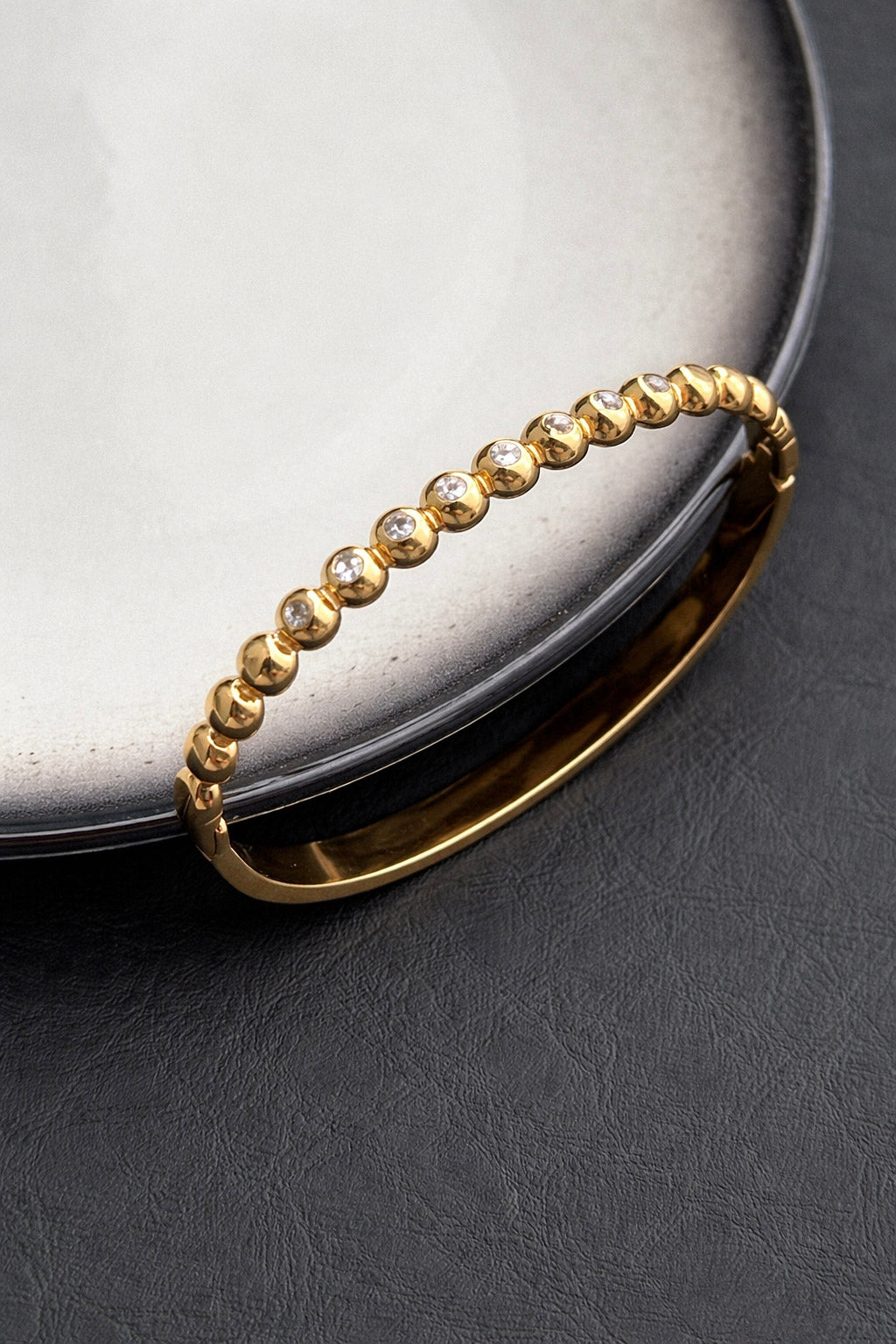 Γυναικείο βραχιόλι χειροπέδα από ατσάλι σε χρυσό χρώμα με πέτρες ζιργκόν