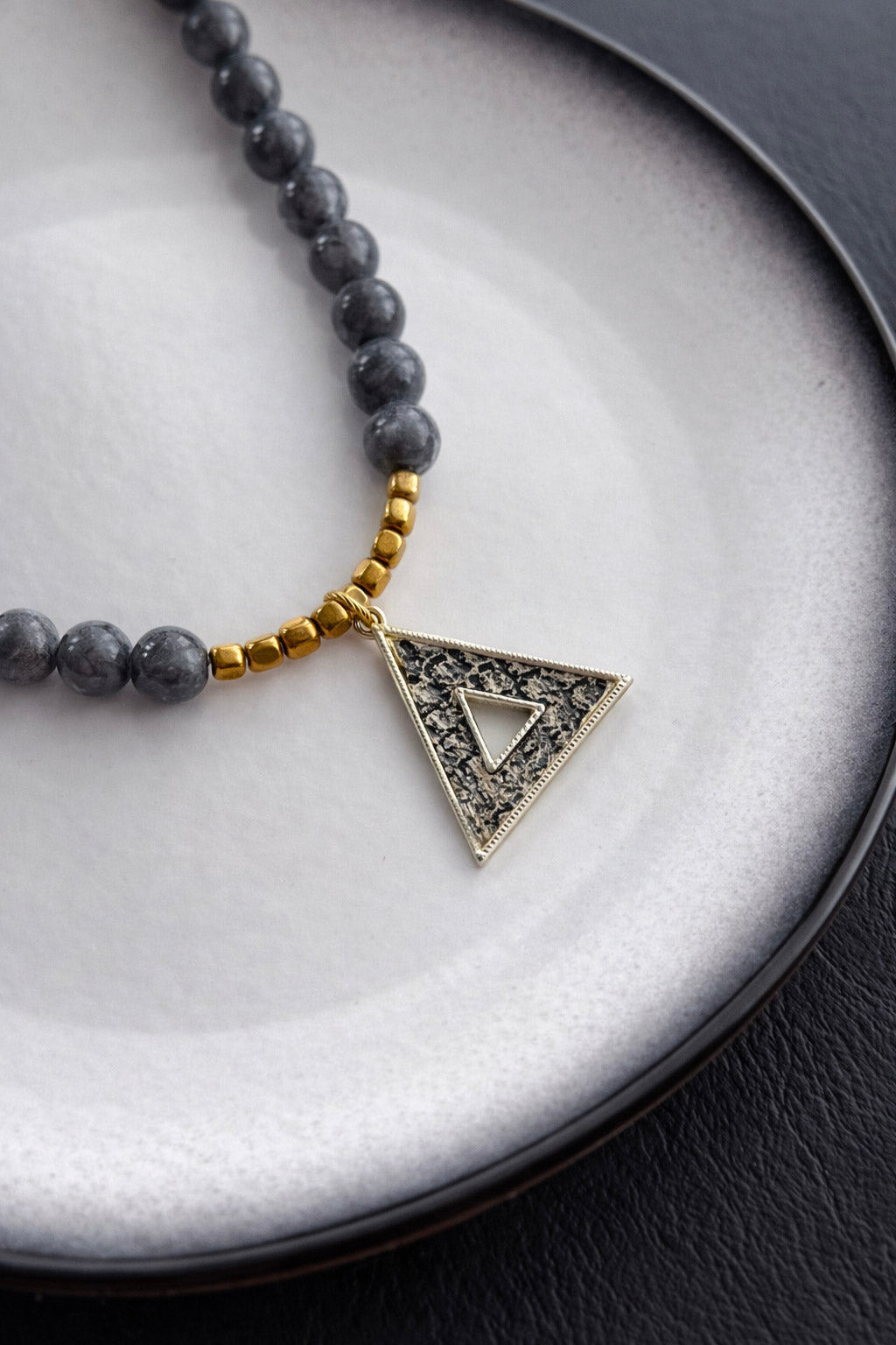Γυναικείο statement κολιέ με γκρι πέτρες και χρυσό γεωμετρικό τριγωνικό στοιχείο από ατσάλι 
