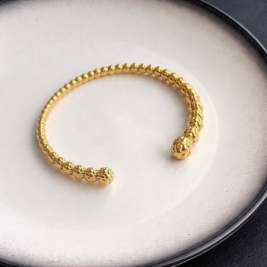 Γυναικείο ανοιχτό βραχιόλι χειροπέδα από ατσάλι σε χρυσό χρώμα με σφυρήλατη υφή